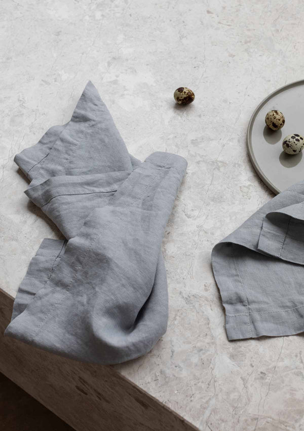 Grey linen napkins on a stone surface with spotted minature eggs