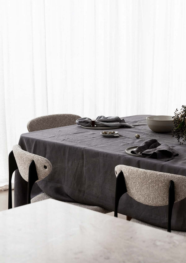 Table set with grey pure linen tablecloth and napkins and chairs around table.