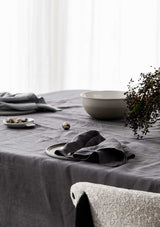 Graphite grey linen napkins and a ceramic bowl on a graphite grey linen tablecloth