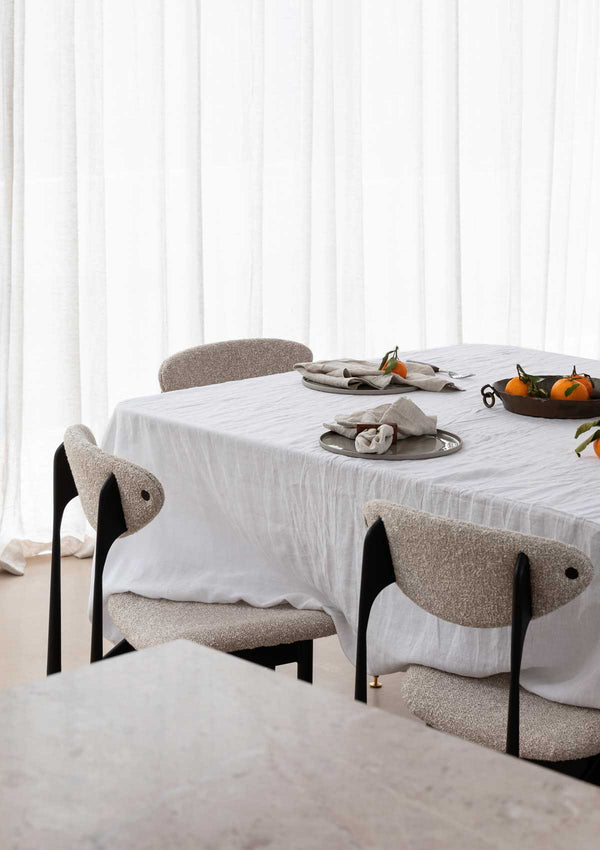 White linen tablecloth on table with mandarins and natural coloured linen napkins.