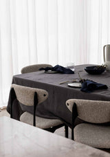Navy napkins set on a grey linen tablcloth with boucle chairs around the table.